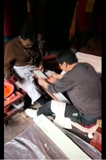 2人の男性が小さな作業台で作業している様子。